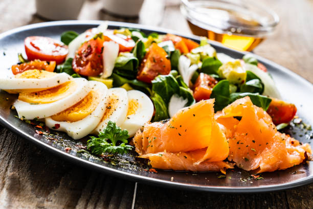 istock Smoked salmon with hard-boiled eggs, avocado and vegetables on wooden table 1256481043