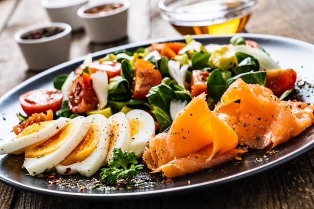 istock Smoked salmon with hard-boiled eggs, avocado and vegetables on wooden table 1256481203