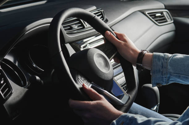 istock Man hold hands on car steering wheel 1256481268