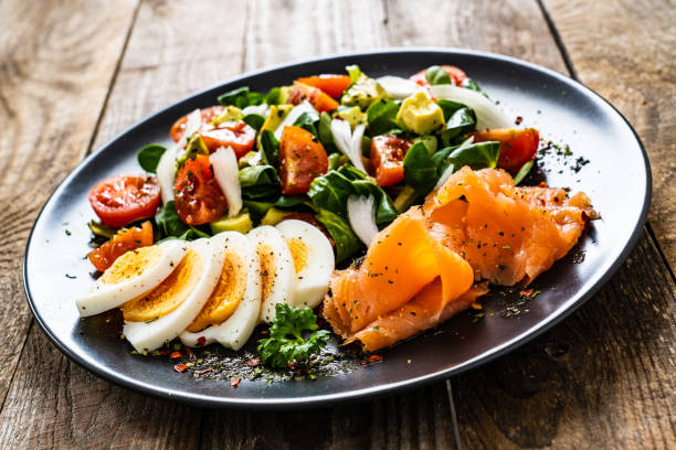 istock Smoked salmon with hard-boiled eggs, avocado and vegetables on wooden table 1256481846