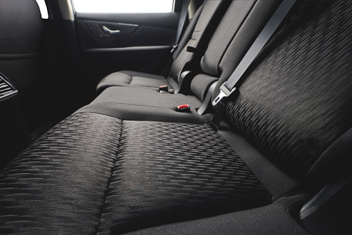 Close up of clean cloth car back seat with safety belts