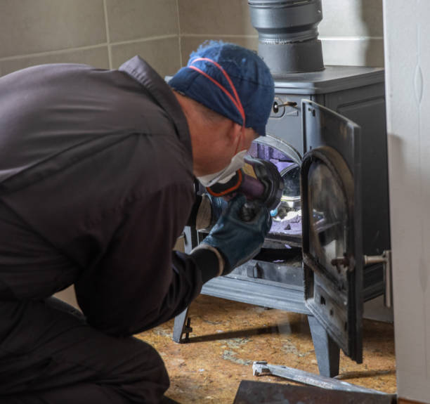 istock Chimney sweep inspecting a log mixed fuel burner chimney with face covering and protective clothes assessing the chimney for blockages. 1256484931
