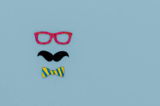 istock Concept image with glasses, moustache and bow tie on light blue background as resource for creative projects, copy space on the right 1256486495