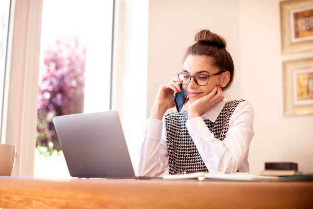 istock Confident young businesswoman making a phone call while working on laptop at home 1256487975