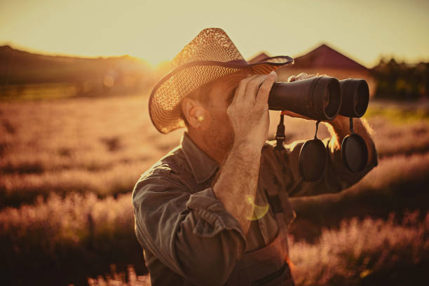 istock Senior male farmer with binoculars in lavender field 1256489483