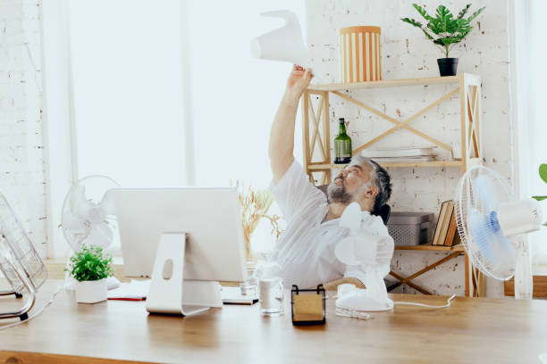 istock Businessman, manager in office with computer and fan cooling off, feeling hot, flushed 1256489696