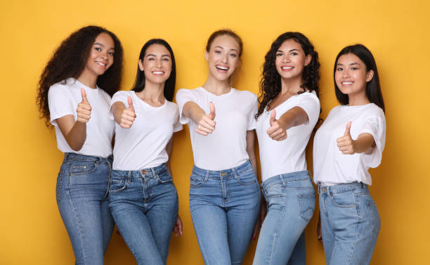 istock Multiethnic Women Gesturing Thumbs-Up Smiling To Camera Standing In Studio 1256490930