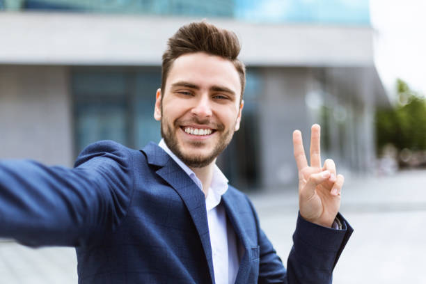 istock Smiling young businessman using video chat or taking selfie at city center 1256493285