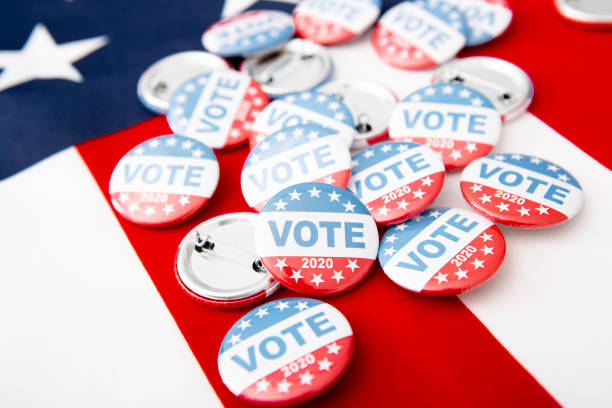 pila patriottica di spille a bottone sullo sfondo della bandiera degli stati uniti - voting election badge straight pin foto e immagini stock