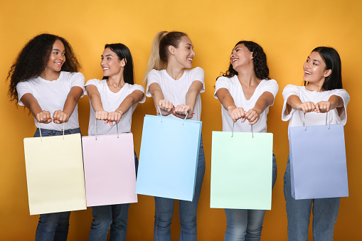 Shopping Concept. Joyful Shopaholics Women Holding Empty Shopper Bags Posing On Yellow Studio Background. Panorama, Mockup