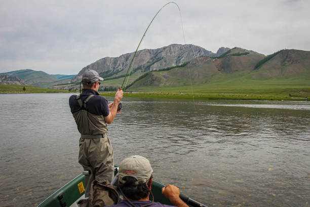 A fisherman with a Taimen Trout on the end of his line in Mongolia stock photo