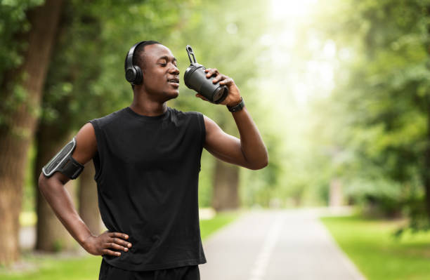 Athletic black man drinking protein while training at park Sportfood concept. Athletic black man drinking protein while training at park, free space sportsperson stock pictures, royalty-free photos & images