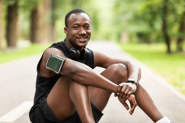 istock Happy black sportsman sitting on park path, resting 1256499023