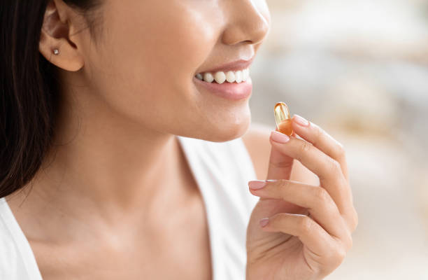 Cropped of asian girl holding capsule of food supplement Cropped of asian girl holding capsule of food supplement, copy space omega 3 stock pictures, royalty-free photos & images