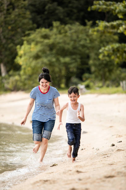 istock mother chasing little boy on the beach 1256500774