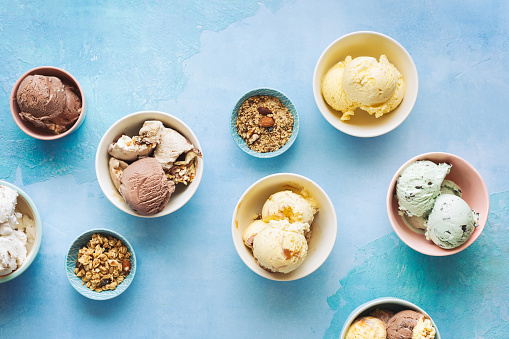 Various ice cream desserts in bowls on rustic blue background, Top view, blank space