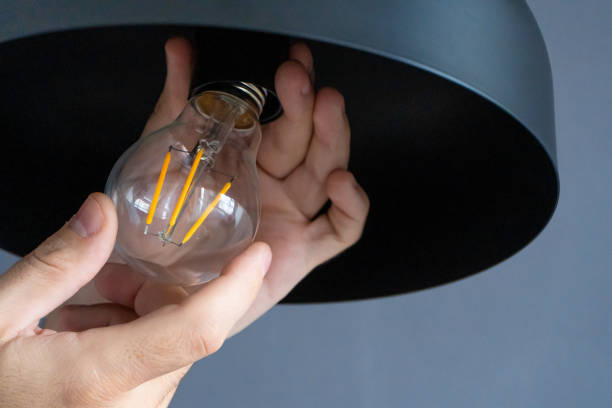 istock Close-up. A hand changes a light bulb in a stylish loft lamp. Spiral filament lamp. Modern interior decor. 1256506216