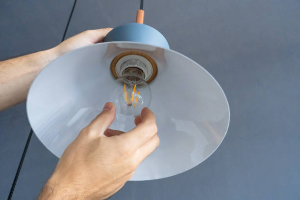 istock Close-up. A hand changes a light bulb in a stylish loft lamp. Spiral filament lamp. Modern interior decor. 1256508215