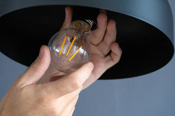 istock Close-up. A hand changes a light bulb in a stylish loft lamp. Spiral filament lamp. Modern interior decor. 1256509178