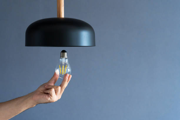 istock Close-up. A hand changes a light bulb in a stylish loft lamp. Spiral filament lamp. Modern interior decor. 1256509634