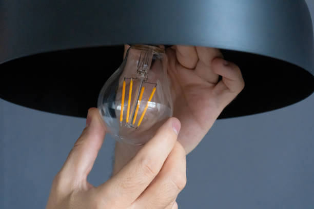 istock Close-up. A hand changes a light bulb in a stylish loft lamp. Spiral filament lamp. Modern interior decor. 1256509675