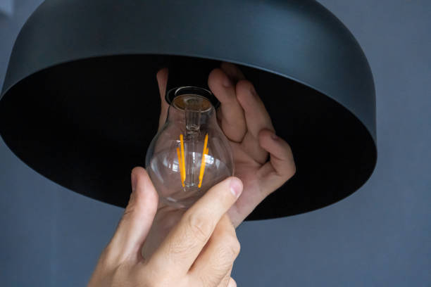 istock Close-up. A hand changes a light bulb in a stylish loft lamp. Spiral filament lamp. Modern interior decor. 1256510797