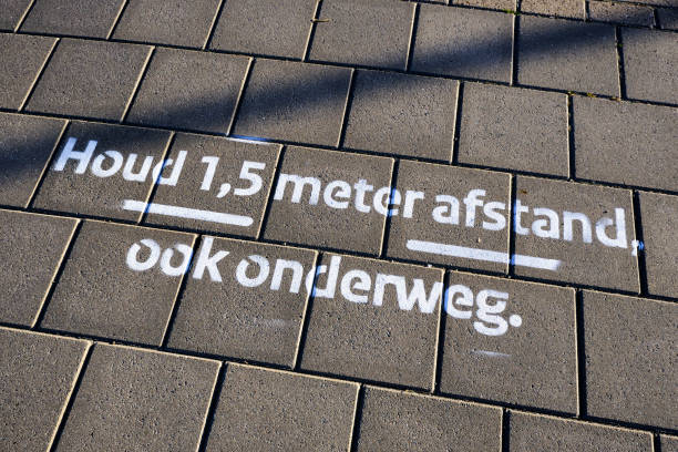 istock Drawing on pavement in Dutch letters means, 'Keep 1.5 meter social distancing, also on the road'. Coronavirus measures and rules 1256511911