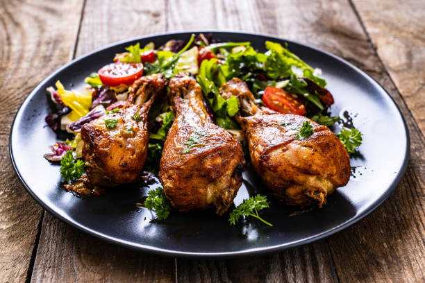 istock Roast chicken drumsticks and vegetables served on wooden table 1256512606