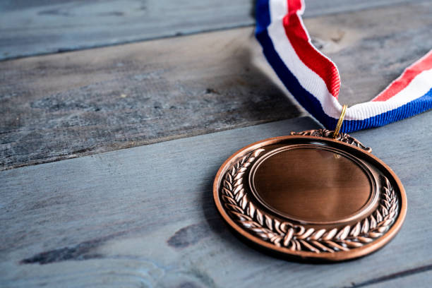 istock Bronze medal on wooden table 1256514214