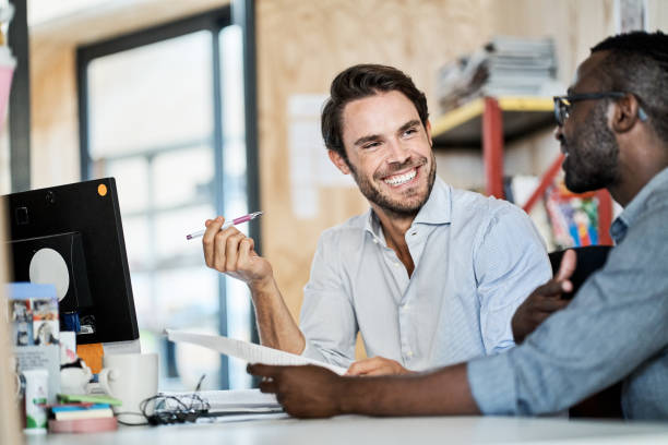istock Diverse young designers smiling while discussing work together in an office 1256514759