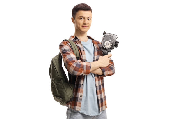 istock Smiling guy with a backpack holding a vintage 8mm camera 1256516399