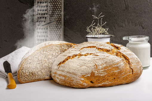 Freshly baked artisan sourdough bread with a sourdough starter on a kitchen countertop