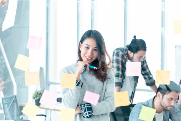istock Diversity creative design team meeting using adhesive note planning strategy with business partners. Marketing teamwork working together in conference room. Multi-ethnic group brainstorming using note pad trust in team 1256519775