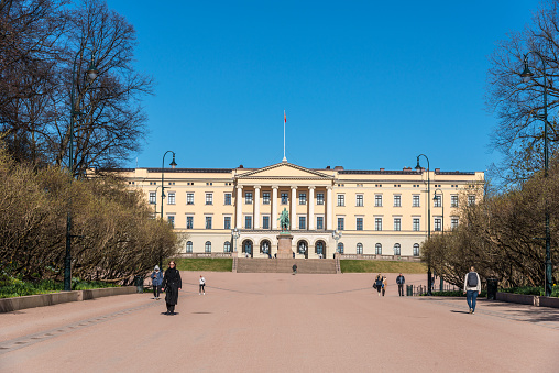Oslo, Norway - April 26. 2018. The royal residence or royal palace is a landmark in Oslo. The wide path to the castle, which is visible from afar, is usually used by many people. However, in the early morning hardly anyone is out and about in the bright sunshine.