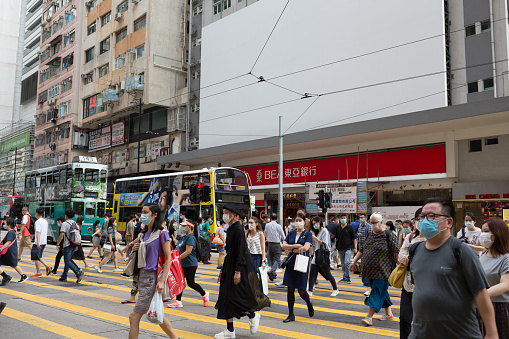 Hong Kong, Hong Kong - July 15, 2020 : People wearing face masks walk past Hennessy Road in Causeway Bay Shopping District, Hong Kong.