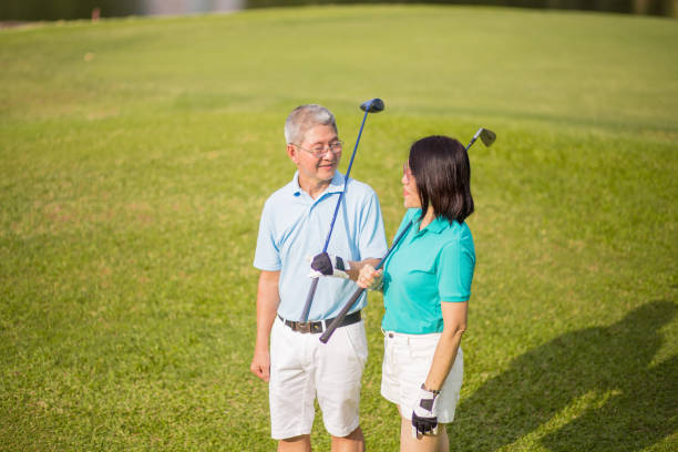 istock Two senior couple walking along golf course and smiling 1256523809
