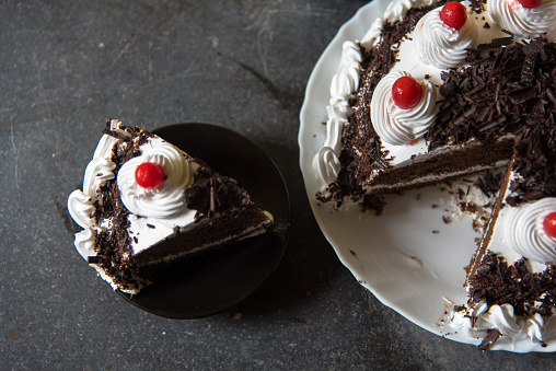 Black forest cake and a slice of it on a background with use of selective focus