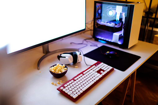 Photo of a work desk with computer equipment and snacks on top of it