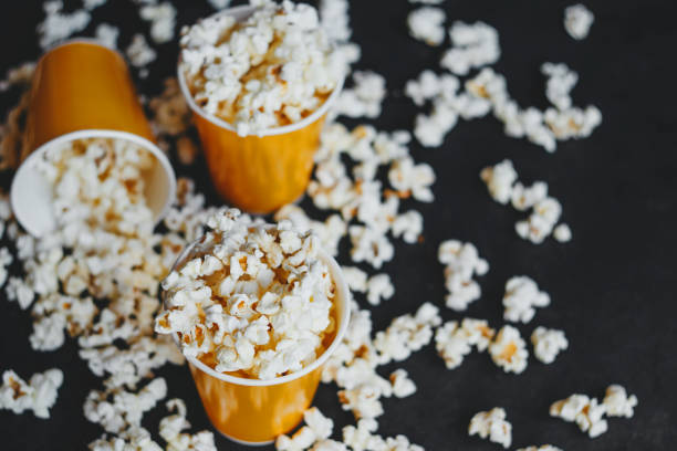 istock Salted popcorn in orange paper cups, on black background 1256525729