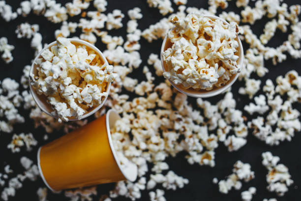 istock Salted popcorn in orange paper cups, on black background 1256525778