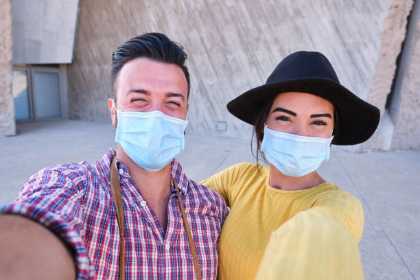 Happy man and girlfriend doing self portrait with masks stock photo