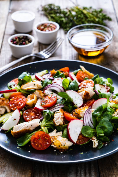 salade césar - salade de légumes avec la viande de poulet rôtie sur fond en bois - side salad tomato spinach lettuce photos et images de collection