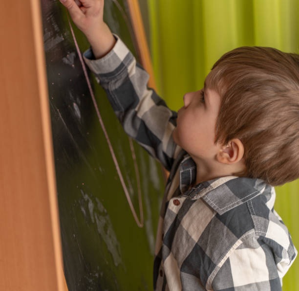 istock Little boy draws chalk on school board 1256527655