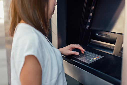 Close-up shot of a woman withdrawing money from a cash machine