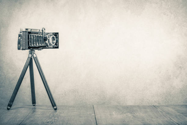 câmera de filme manual desatualizada retrô por volta dos anos 1950 na mesa de madeira. foto de sépia estilo vintage - photographer camera tripod paparazzi photographer - fotografias e filmes do acervo