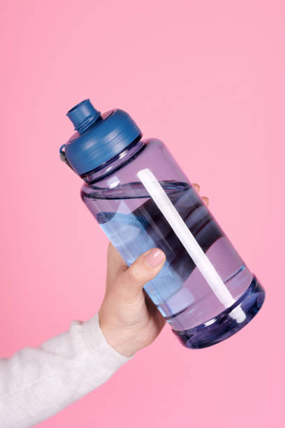 istock Hand with sport water bottle. Isolated on pink background. 1256531832