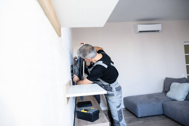 Two professional technicians, workers in uniform installing, fixing mount tv, television on the wall indoors. Construction, maintenance and repair concept