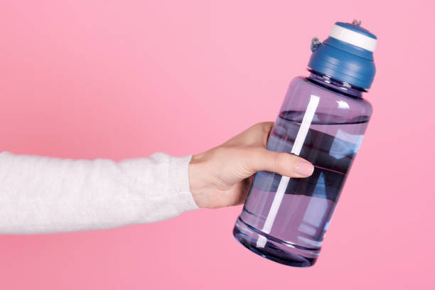 istock Hand with sport water bottle. Isolated on pink background. 1256531887