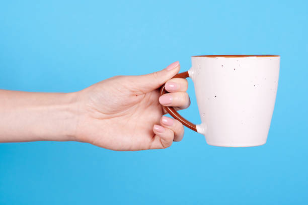 istock Hand with white coffee cup. Isolated on blue background. 1256532446