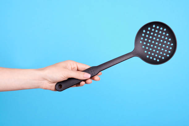 istock Hand with black plastick ladle utensil. Isolated on blue background. 1256532471